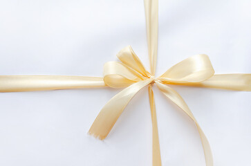 Fototapeta premium gift is tied with beige ribbon. Flat lay, space text. golden ribbon, bow, crossed, isolated on white