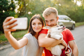 Selfie time. Young couple together with their beloved pet on a walk doing selfie.The concept of an...