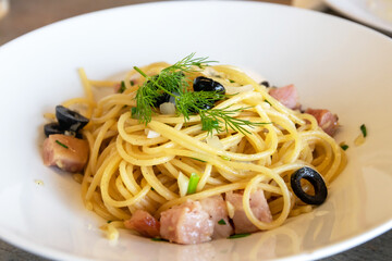 Spaghetti with guanciale, garlic, olive oil and chili on white plate. 
