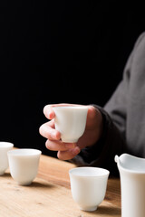 White ceramic teacup in Jingdezhen, China, on wooden table, indoor dark background,traditional chinese tea set