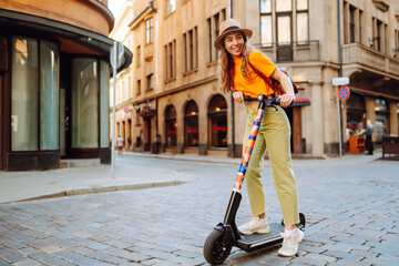 Young woman driving electric scooter through the city. Active life. Ecological transportation concept.