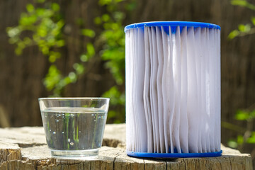 The replacement Pool Filter Cartridge. Filter reuse. Glass of pure water. Outdoor. Sunlight. Copy...