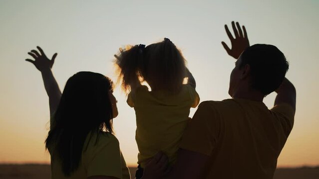 Happy family together pull their hands to sky. Family team people silhouette at sunset in park. Freedom outdoors.Group of people at sunset in park. Victory people pull their hands up. Family in nature