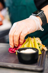 chef hand lay out pickled cucumber and cabbage on plate in kitchen