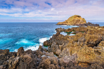 Lava rocks natural volcanic pools in Porto Moniz, Madeira island, Portugal. Dramatic seascape. Beauty of nature concept background. Panoramic view.
