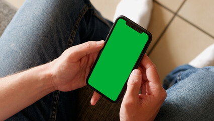 Holding a Green Screen Smartphone on the Couch at Home
