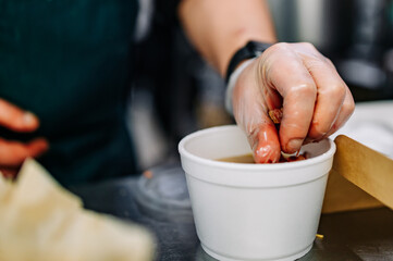 chef hand cooking Vegetable soup in a disposable plastic bowl