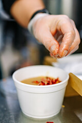 chef hand cooking Vegetable soup in a disposable plastic bowl