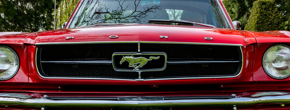 Earsham, Norfolk, UK – April 30 2023. The grille and horse badge of a classic Ford Mustang muscle car on display at a small and local outdoor car show