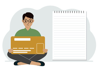 A man sits cross-legged in his hands holding a large credit card next to a close-up notepad for text. Concept of credit card, expense planning, income planning.