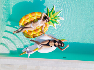 lgbt couple drinking and hugging each other in swimming pool, view from above