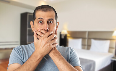 Fototapeta na wymiar Shocked man covering his mouth with hands at hotel