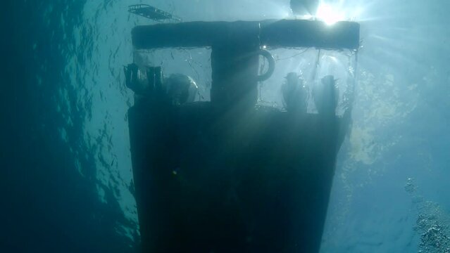 Under water film from tropical waters of Thailand - 90 degree view upwards of the aft part of a diving boat with glaring sun  rays