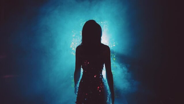 dark shadow mysterious silhouette fantasy woman walking in black night garden in fog fairytale portal arch flowers, art neon blue magic light. Mystery lady Gothic Girl princess in smoke back rear view