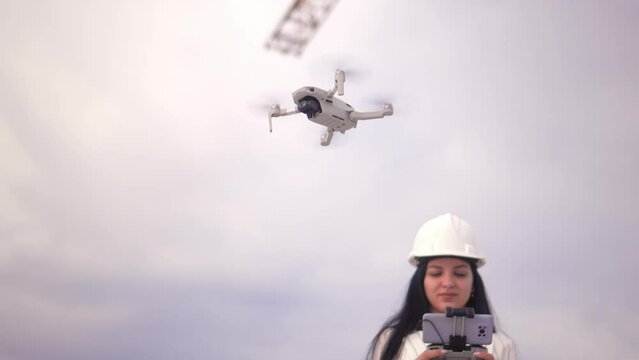Civil Engineering Unmanned Aerial Vehicle Over Construction Site Survey for Land Plot and Construction Project. Young beautiful woman engineer uses drone on construction site against mountains.