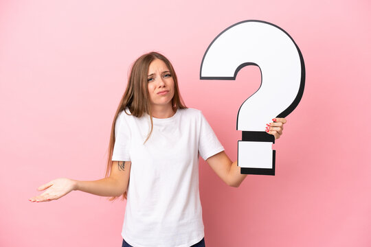 Young Lithuanian woman isolated on pink background holding a question mark icon and having doubts
