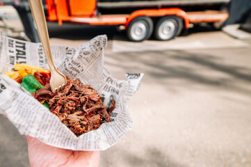 man holds pulled pork and french fries with sauce in hands. Street food, fast food outdoor