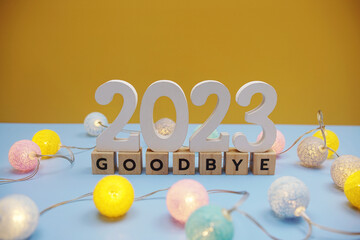 Goodbye 2023 letters with LED cotton balls decoration on blue background