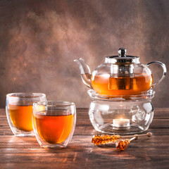 Black tea in a glass teapot and cups. On a dark background. Tea concept.
