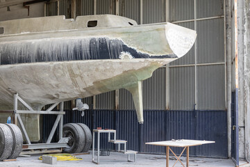 Fiberglass yacht being repaired at a shipyard. Boat restoration