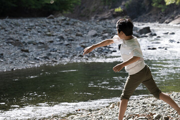 Fototapeta premium Backlit Image of elementary school children playing on a river in summer or children traveling outdoors or camping