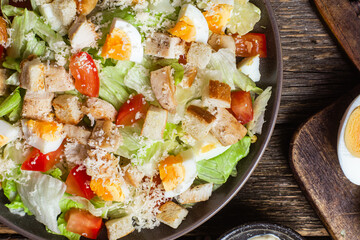 Salad of iceberg leaves, chicken, eggs and tomatoes in a plate. Caesar salad