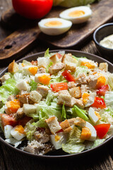 Salad of iceberg leaves, chicken, eggs and tomatoes in a plate. Caesar salad