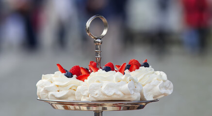 Pavlova desserts embellished with summer berries fruits, raspberries, strawberries and blueberries, closeup. - obrazy, fototapety, plakaty
