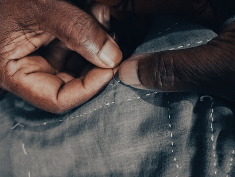 Closeup of a woman's hands sewing with niddle applique work making bed sheet. Concept of self employment woman and Female entrepreneurs in Bangladesh. Katha shelai. Nakshi katha