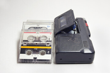 dictaphone and stack of neatly layed cassettes in transparent plastic covers. Blue microcassette inserted for use
