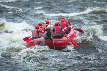 Red raft boat during whitewater rafting extreme water sports on water rapids, kayaking and canoeing on the river, water sports team with a big splash of water