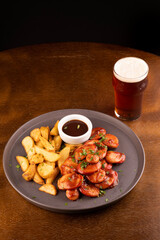 portion of bock sausages with rustic fries and barbecue sauce and curry pint of pale ale on a round table