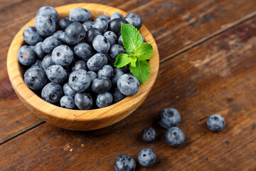 Freshly picked blueberries in wooden bowl on wooden background.  Concept of healthy and dieting eating.