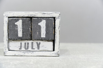 Calendar for July 11, made of wooden cubes, on gray background.With an empty space for your text.Chocolate day.