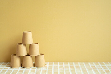 Pyramid stack of brown cup on desk. yellow background. business develop achievement growth concept