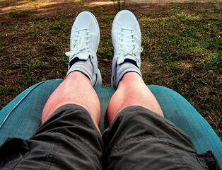 Legs and Feet Lazing on a Sun Lounger with Shorts and Sneakers