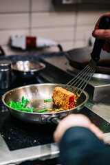 man chef cooking fried tuna fish and green bean in frying pan on kitchen