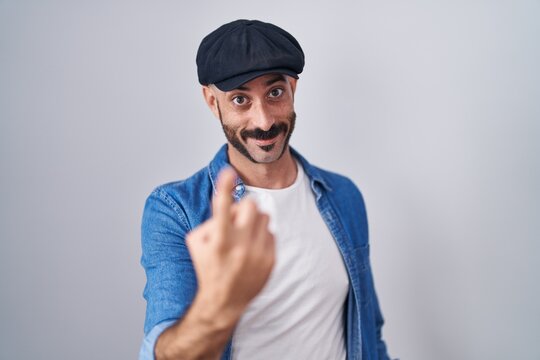 Hispanic man with beard standing over isolated background beckoning come here gesture with hand inviting welcoming happy and smiling