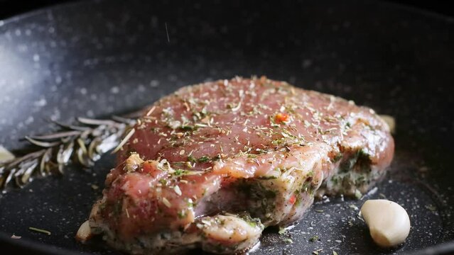 Chef sprinkling with seasoning juicy staek on the pan. Process of roasted steak cooking