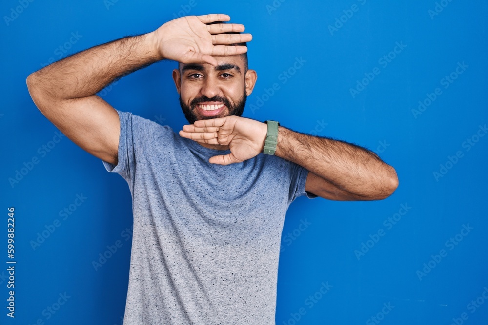 Sticker middle east man with beard standing over blue background smiling cheerful playing peek a boo with ha