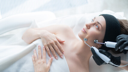 Young caucasian woman on microcurrent therapy procedure. Beautician's office.