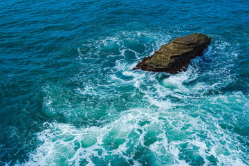 Obraz premium Rock on the ocean with waves surrounding. Pacitan, East Java, Indonesia.