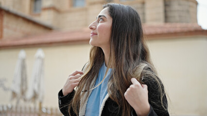 Fototapeta na wymiar Young beautiful hispanic woman student smiling confident standing at street