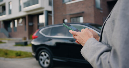 Close up of female hands holding phone, typing on screen, chatting in social network, writing message, browsing mobile device apps at area outdoors