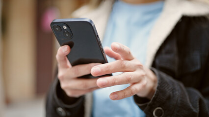 Young beautiful hispanic woman using smartphone at street