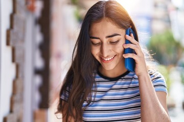 Young hispanic girl smiling confident talking on the smartphone at street