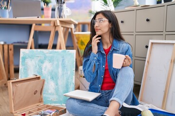 Young hispanic girl artist smiling confident drinking coffee at art studio