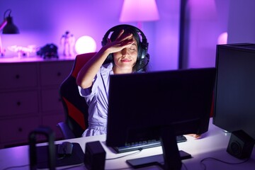 Young beautiful hispanic woman streamer stressed using computer at gaming room