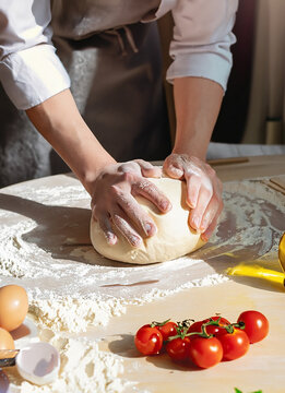 hands of the cook in the kitchen sprinkle the dough with flour. dough for pizza.
