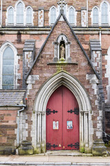 Fototapeta na wymiar Old weathered door with sculpture Saint Vincent Church nd Presbytery in Cork Munster province in Ireland Europe